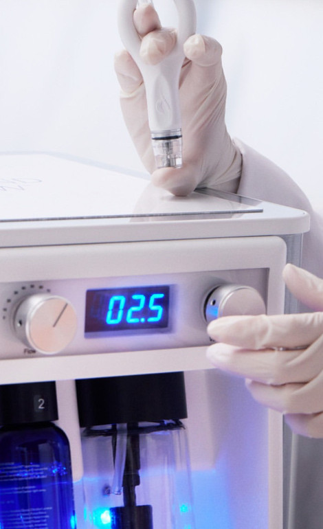 En person som bär handskar justerar inställningarna på en enhet med en digital display som visar "0.2.5" och ett synligt blått ljus inuti.