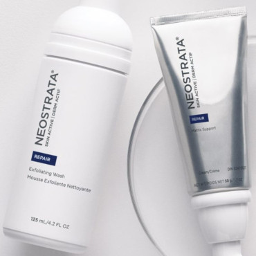 Två Neostrata hudvårdsprodukter: en vit flaska exfolierande tvätt och en silvertub med kräm. Båda märkta "Repair" på ljus bakgrund.